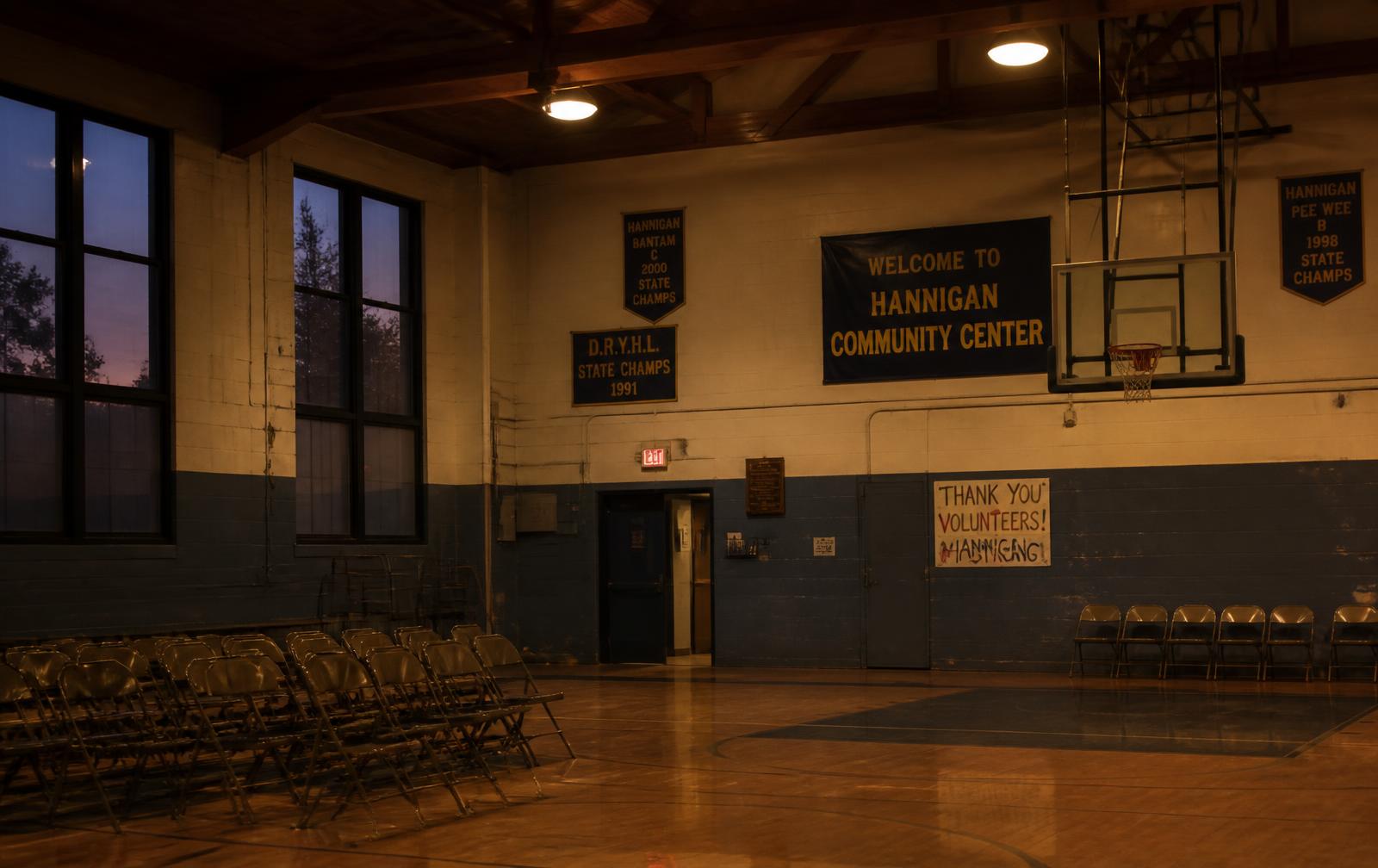 Empty community center gym at dusk with championship banners on the wall